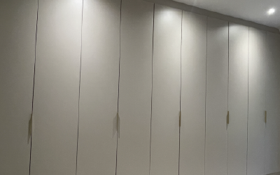Modern hinged wardrobes with slim gold handles and integrated LED lighting.