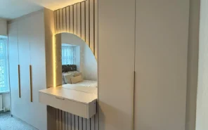 Luxury walk-in wardrobe with central dressing island and open oak shelving.